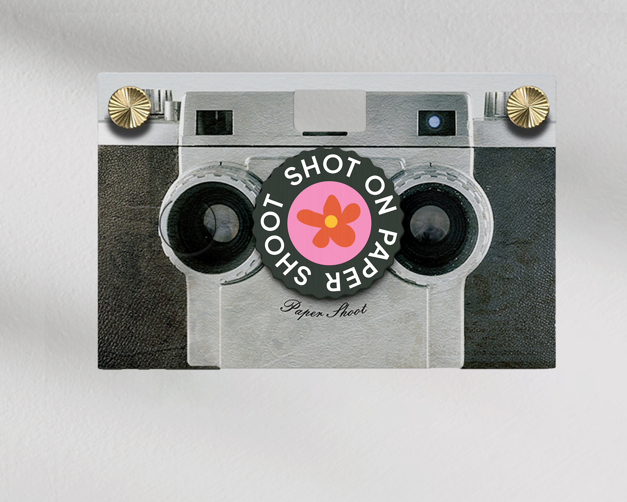 Shot on paper shoot text lens cover with red and yellow flower graphic with grip groves on a paper shoot camera 