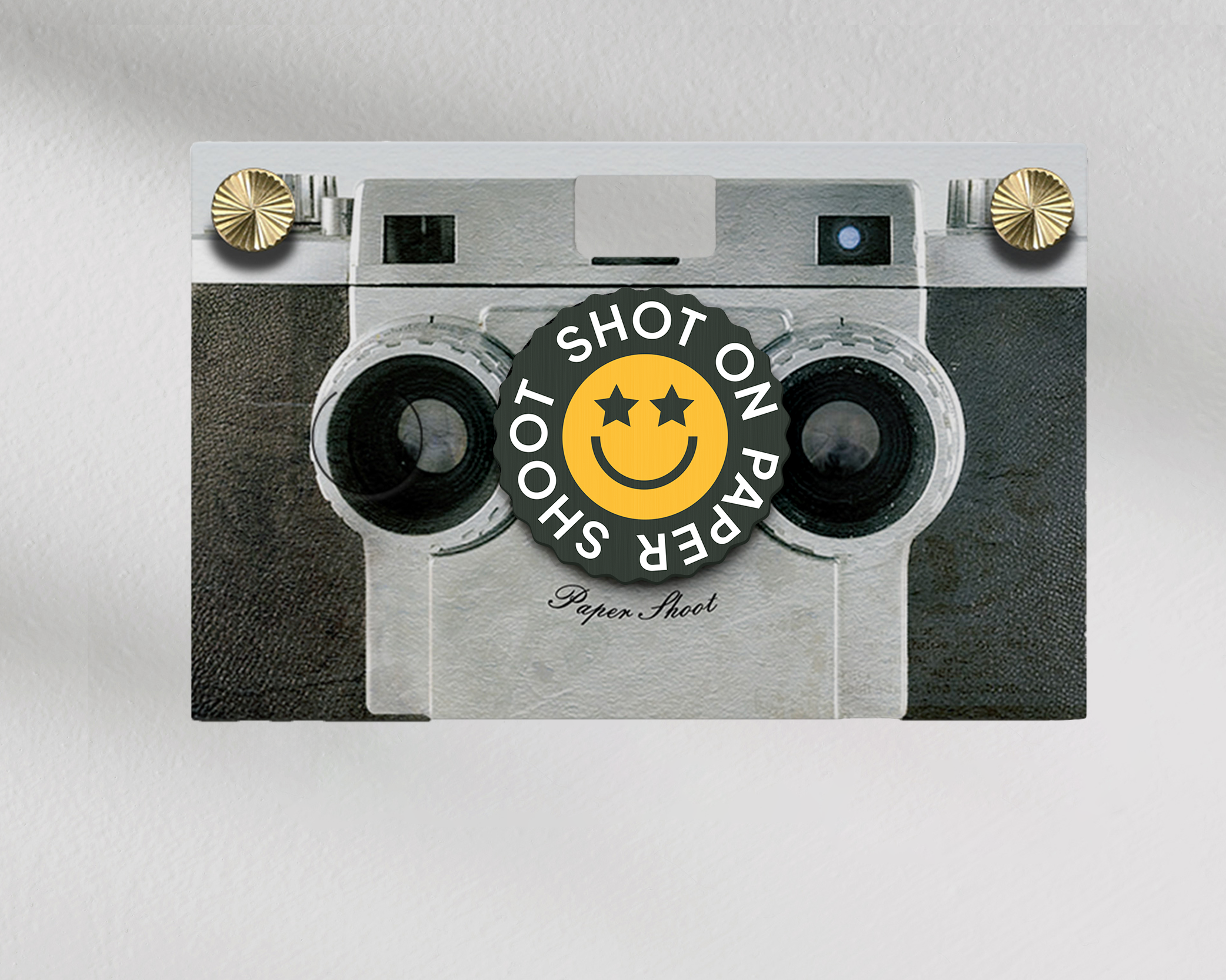 Shot on paper shoot text lens cover with yellow star eyed smiley face with grip groves on a paper shoot camera 